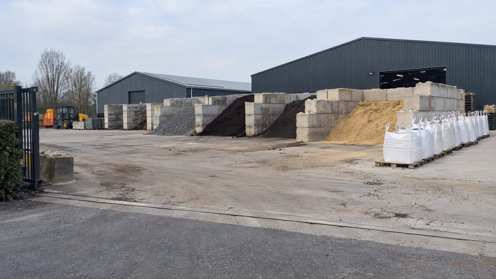 Het terrein met stortvakken van betonblokken, gevuld met granulaat, teelaarde en zand, en een rij big bags op pallets